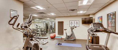 A gym with various exercise equipment, including treadmills, stationary bikes, and weights.