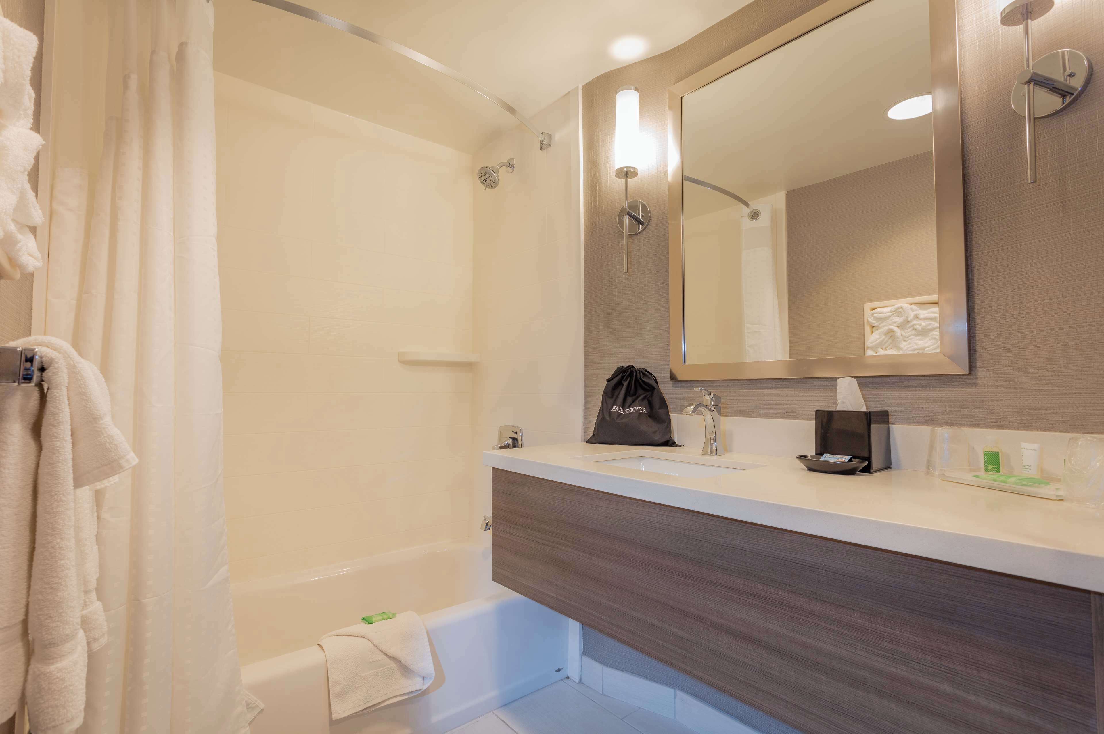 A modern bathroom with a bathtub, a sink, a mirror, and a towel rack.