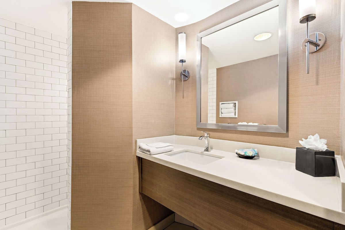 A modern bathroom with a white sink, a mirror, and a towel.