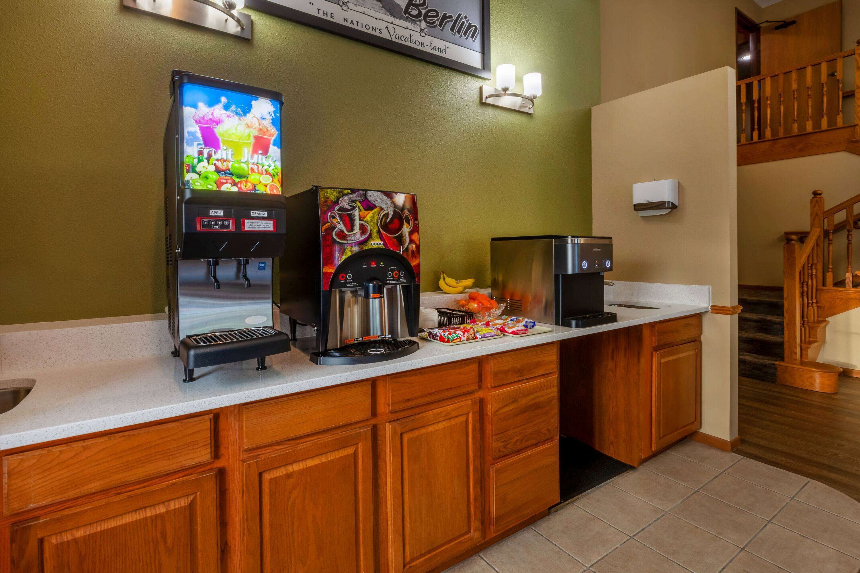 Una cocina de hotel con una máquina de café, un dispensador de zumo de frutas y un cartel que dice 'Berlín'.
