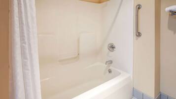 A white bathtub with a showerhead, a grab bar, and a towel rack.