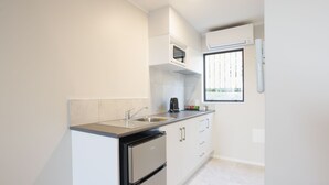 A modern kitchen with a stainless steel sink, a built-in oven, and a window with a view of greenery. - Bk's Pohutukawa Lodge (Whangarei)