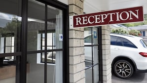 A reception sign, a glass door, and a white car parked outside. - Bk's Pohutukawa Lodge (Whangarei)