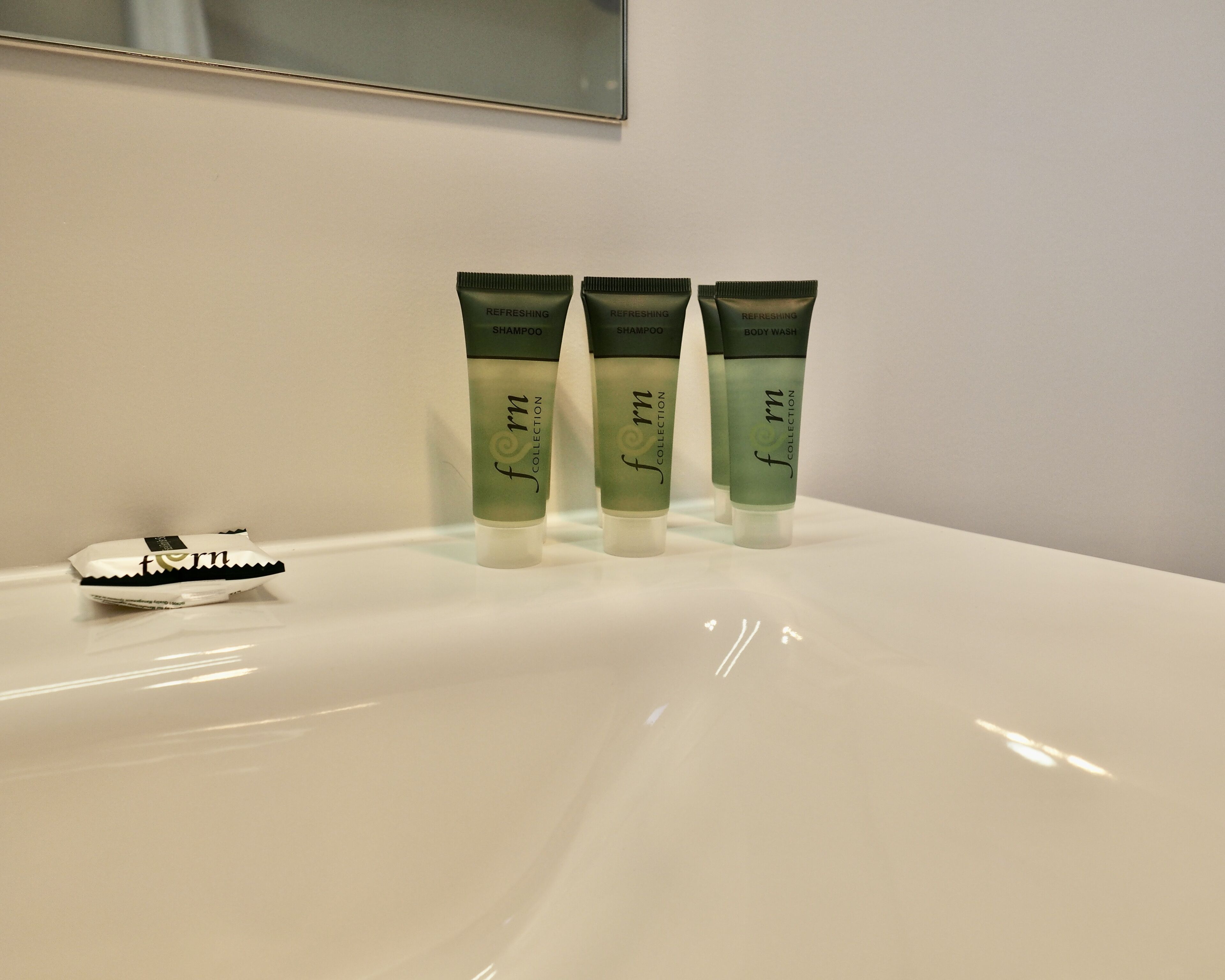 Tres botellas de la colección 'form' de champú y gel de ducha sobre un lavamanos blanco.