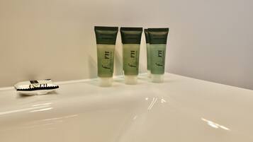 Tres botellas de la colección 'form' de champú y gel de ducha sobre un lavamanos blanco.