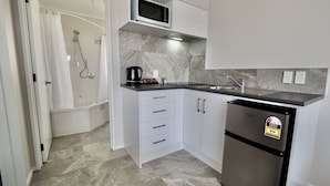 A compact kitchen with a microwave, sink, and refrigerator. - Bk's Pohutukawa Lodge (Whangarei)