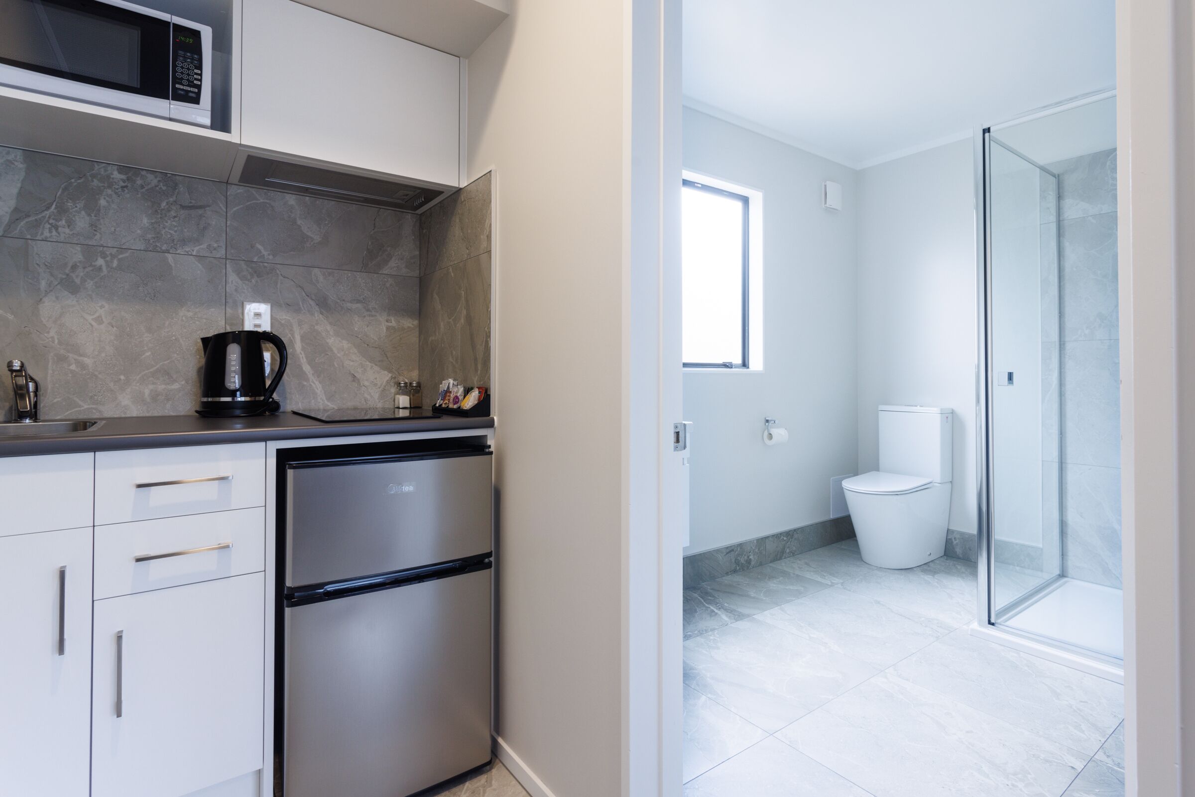 A modern kitchen with a stainless steel refrigerator, a coffee maker, and a microwave.