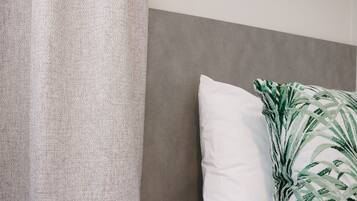 A bed with a grey headboard, a white pillow, and a green patterned pillow.
