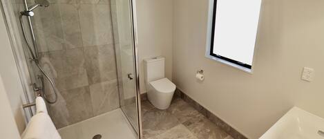A bathroom with a glass-enclosed shower, a toilet, and a sink.