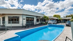A swimming pool area with a building that has a sign reading "Conference Room". - Portmans Motor Lodge (Hastings)