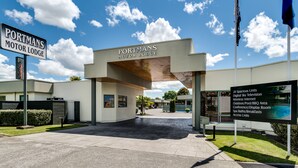 The exterior of Portmans Motor Lodge with a clear sky and a sign listing amenities like 20 spacious units, digital sky television, and an outdoor pool. - Portmans Motor Lodge (Hastings)