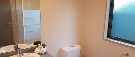 A bathroom with a double sink, a toilet, a window, and a towel rack.