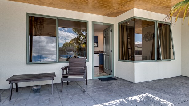 A covered patio with a bench and a door leading to a kitchen area. - Portmans Motor Lodge (Hastings)