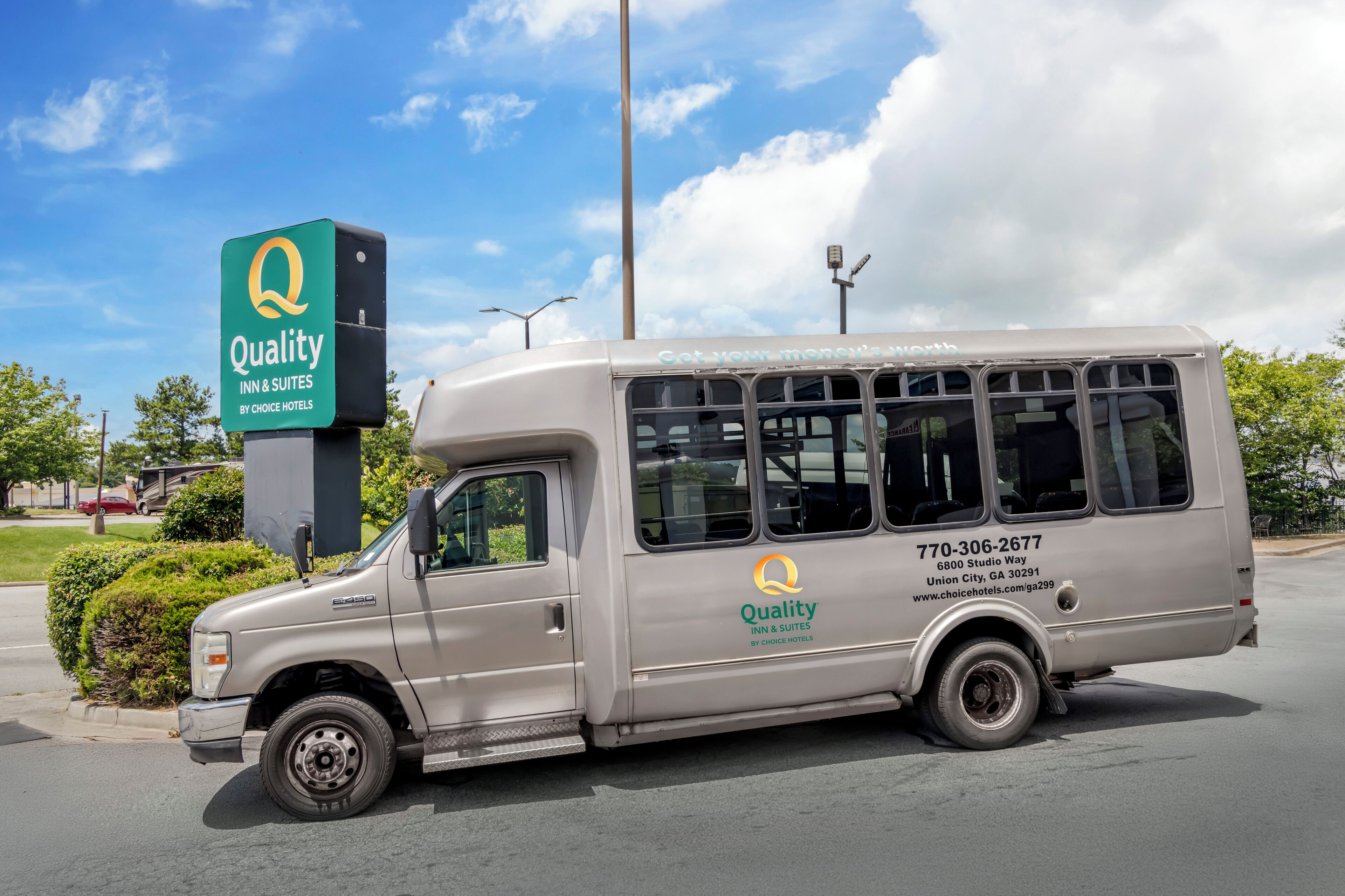 A van with the 'Quality Inn & Suites by Choice Hotels' logo, parked in front of a hotel sign.