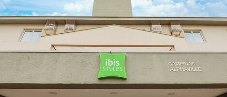 Un edificio con un letrero verde que dice "ibis Styles" y "CAMPINAS ALPHAVILLE" en la fachada.