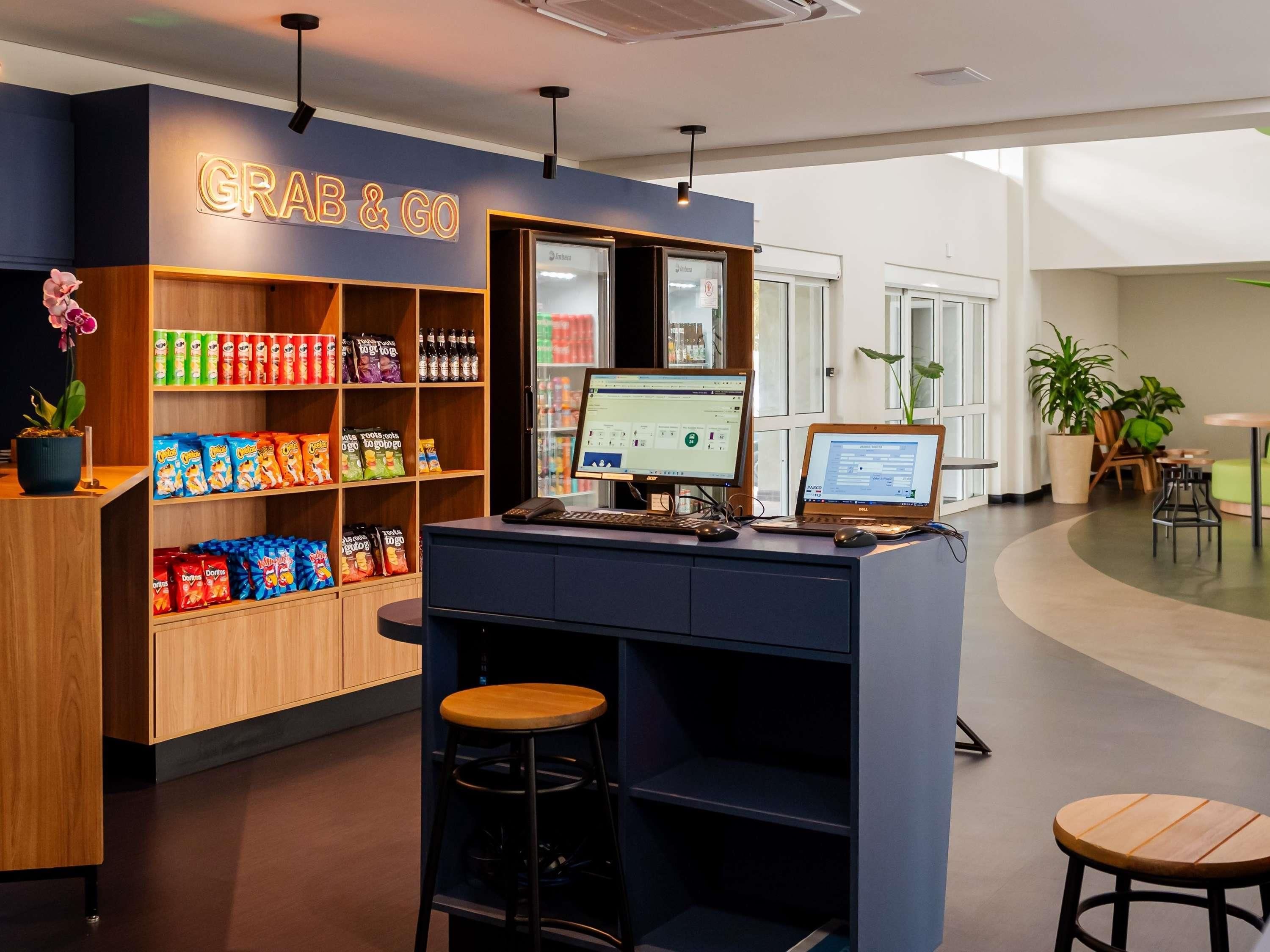 A snack bar with a 'Grab & Go' sign, a computer, and a cash register.