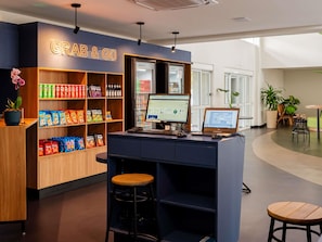 Un bar de aperitivos con un letrero que dice 'Grab & Go', una computadora y una caja registradora.