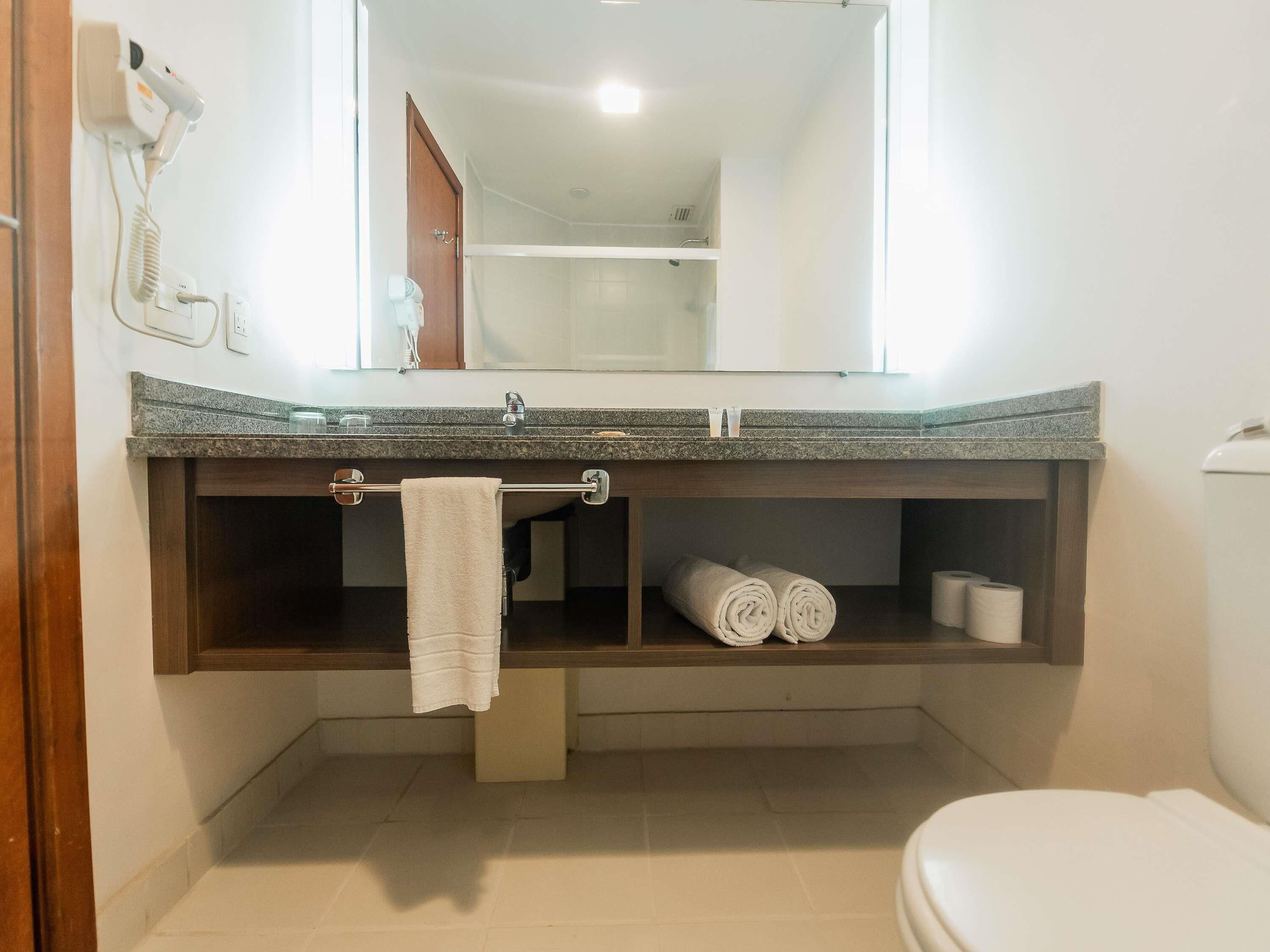 Un baño con encimera de granito, perchero, inodoro y zona de ducha.