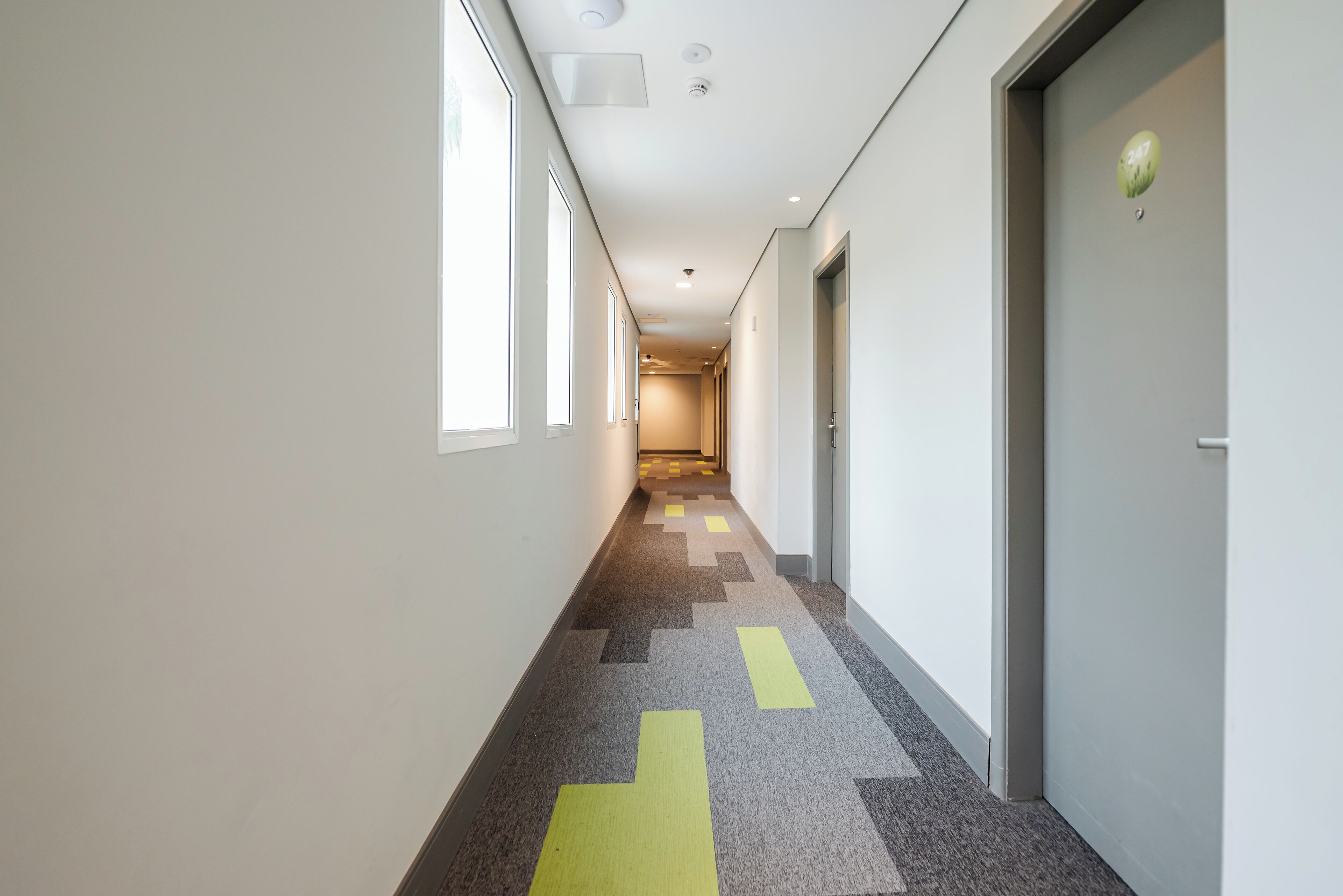 A hallway with a patterned carpet, white walls, and doors on both sides.