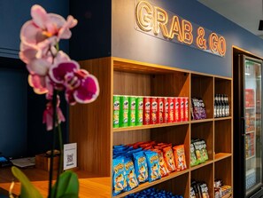 A store with shelves stocked with snacks and a neon sign that reads 'GRAB & GO'. - ibis Styles Campinas Alphaville (Campinas)