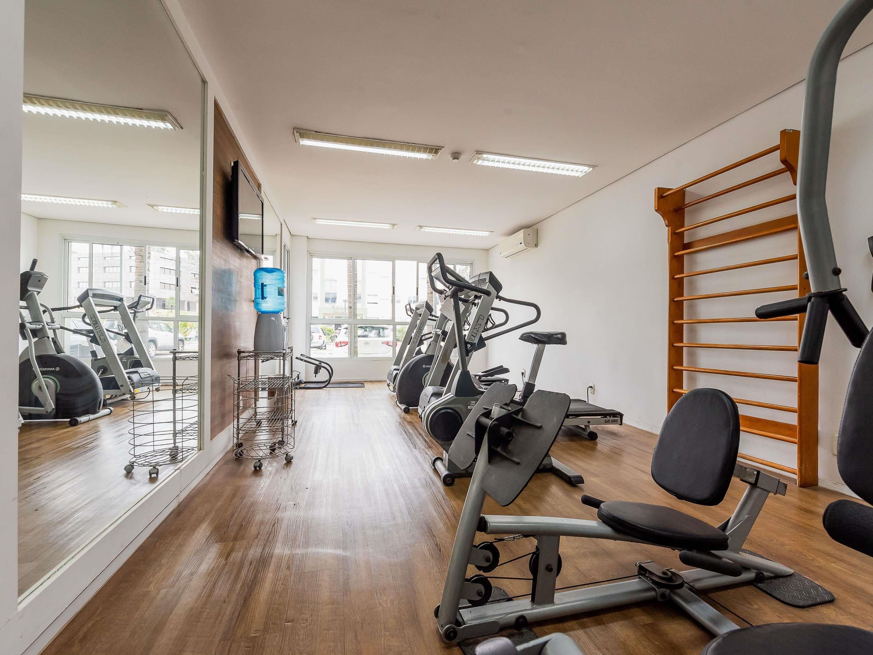 A gym with exercise equipment, a water dispenser, and a large mirror.