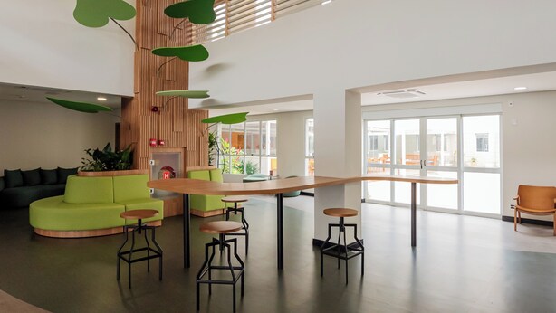 A spacious lobby with a wooden reception desk, green seating, and a large window offering a view of the outdoors. - ibis Styles Campinas Alphaville (Campinas)