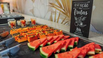 Une table de buffet proposant une variété de fruits et de boissons.