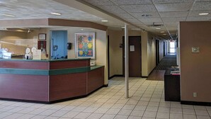 A reception area with a counter, a blue door, and a colorful painting on the wall. - St Clair Inn and Suites (St. Clairsville)