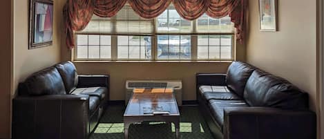 A room with two leather sofas, a small table, and a large window with blinds.