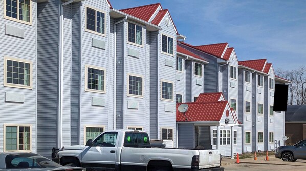 A multi-story building with a red roof, white siding, and multiple windows. - St Clair Inn and Suites (St. Clairsville)