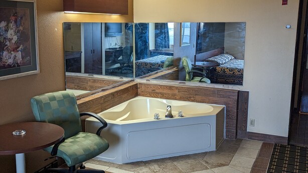 A bathroom with a large bathtub, a chair, and a small table. - St Clair Inn and Suites (St. Clairsville)