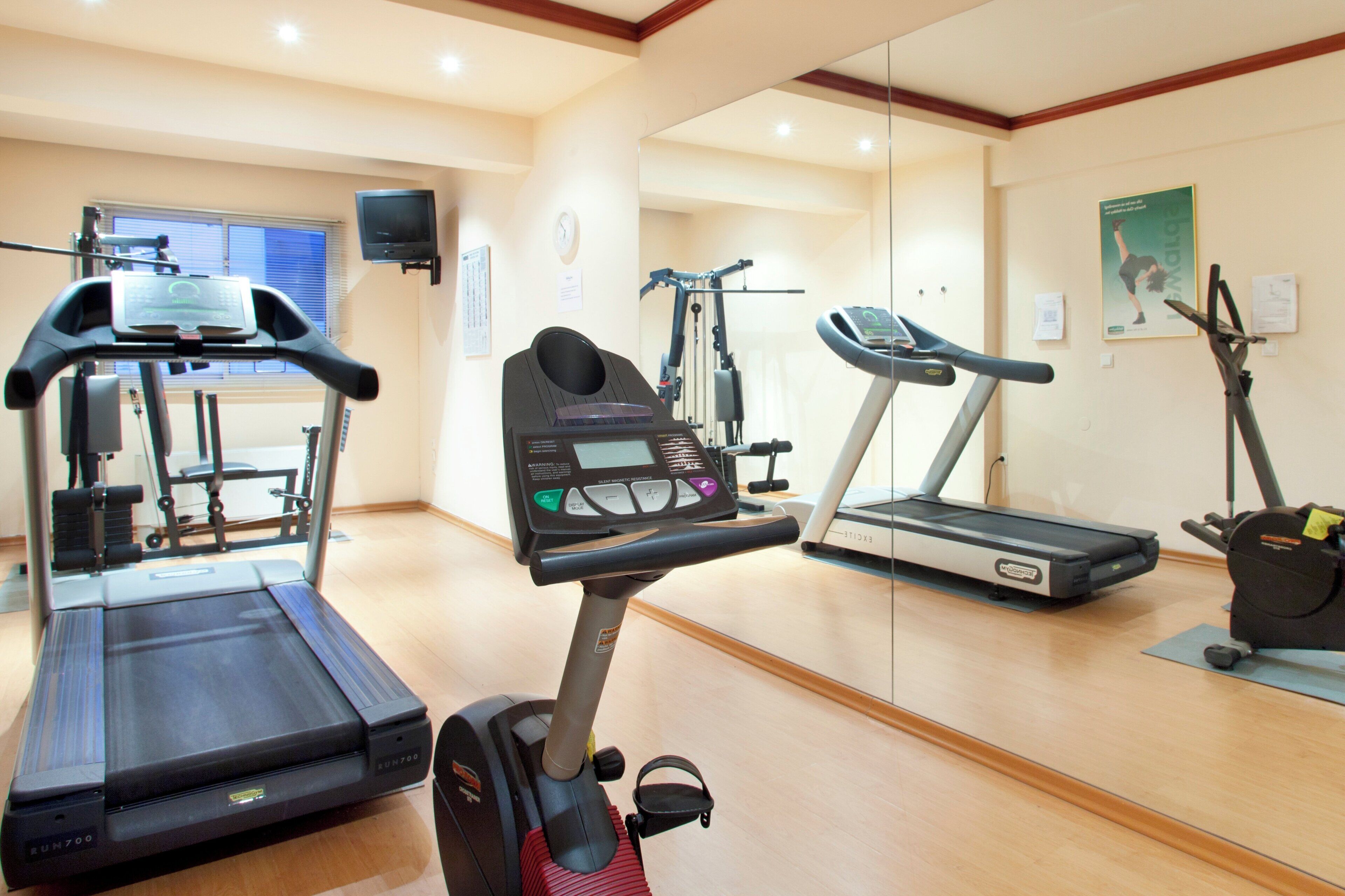 Un gimnasio con diverso equipo de ejercicio, incluyendo cintas de correr, elípticas y bicicletas estáticas.