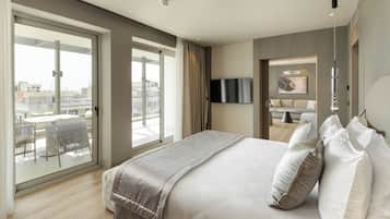 A modern hotel room with a large bed, a TV mounted on the wall, and a balcony with a table and chairs.