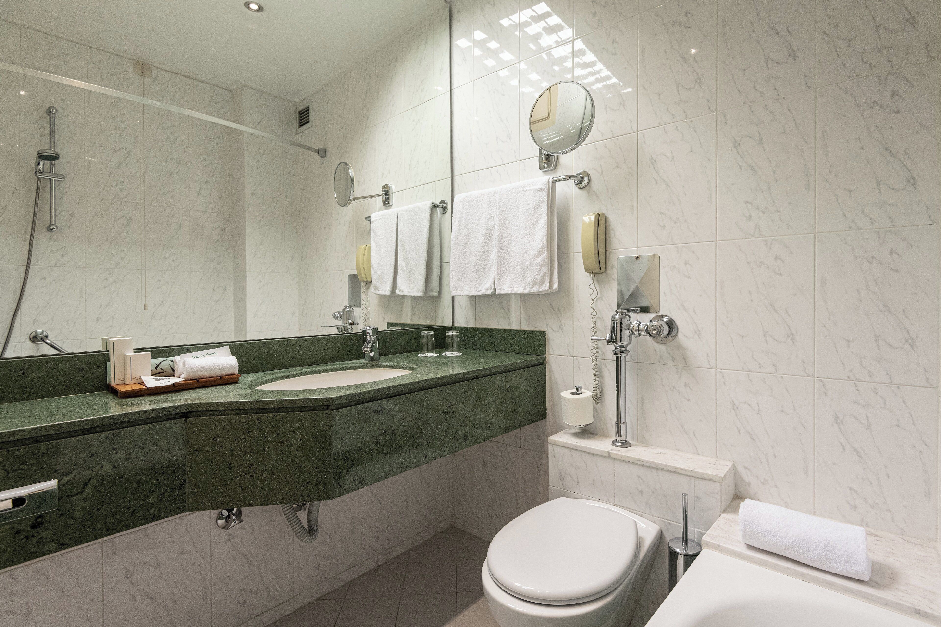 A modern bathroom with a marble sink, a toilet, and a bathtub.