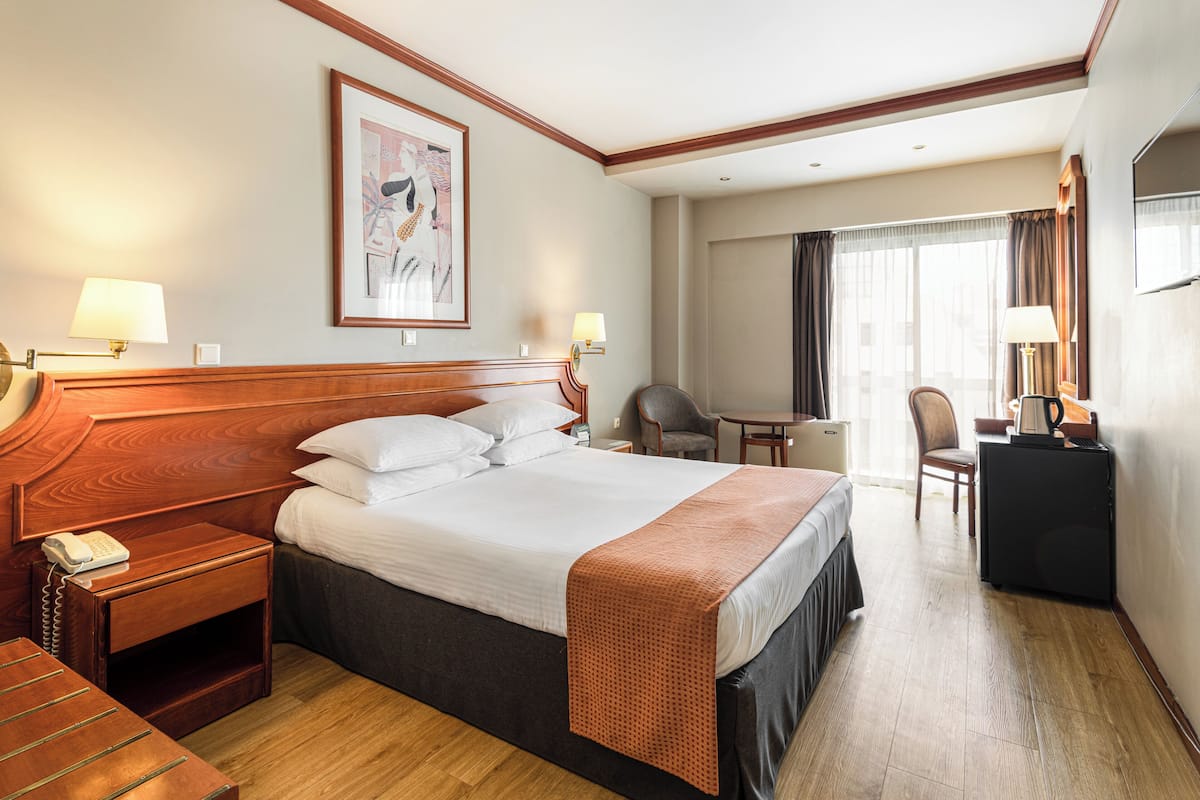 A hotel room with a large bed, bedside tables, a desk, and a chair.