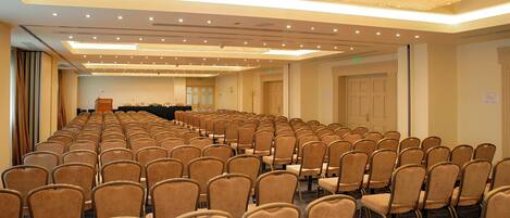 A conference room with rows of chairs, a podium, and a chandelier.
