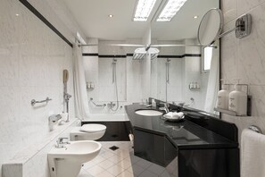 A modern bathroom with a large bathtub, two sinks, a vanity, and a shower area. - Holiday Inn Thessaloniki by IHG (Thessaloniki)