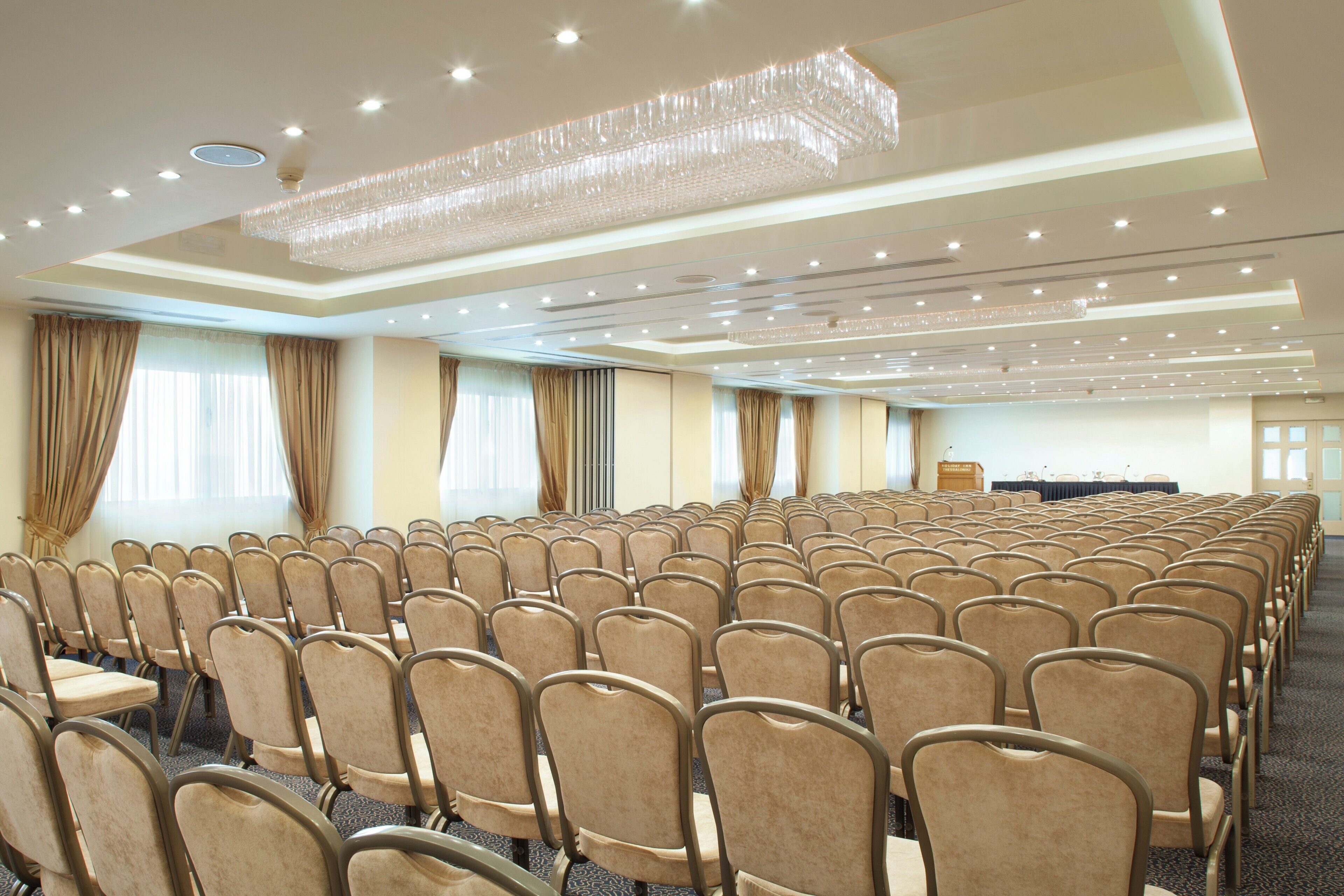 Un salón de conferencias con filas de sillas, un atril y una araña.