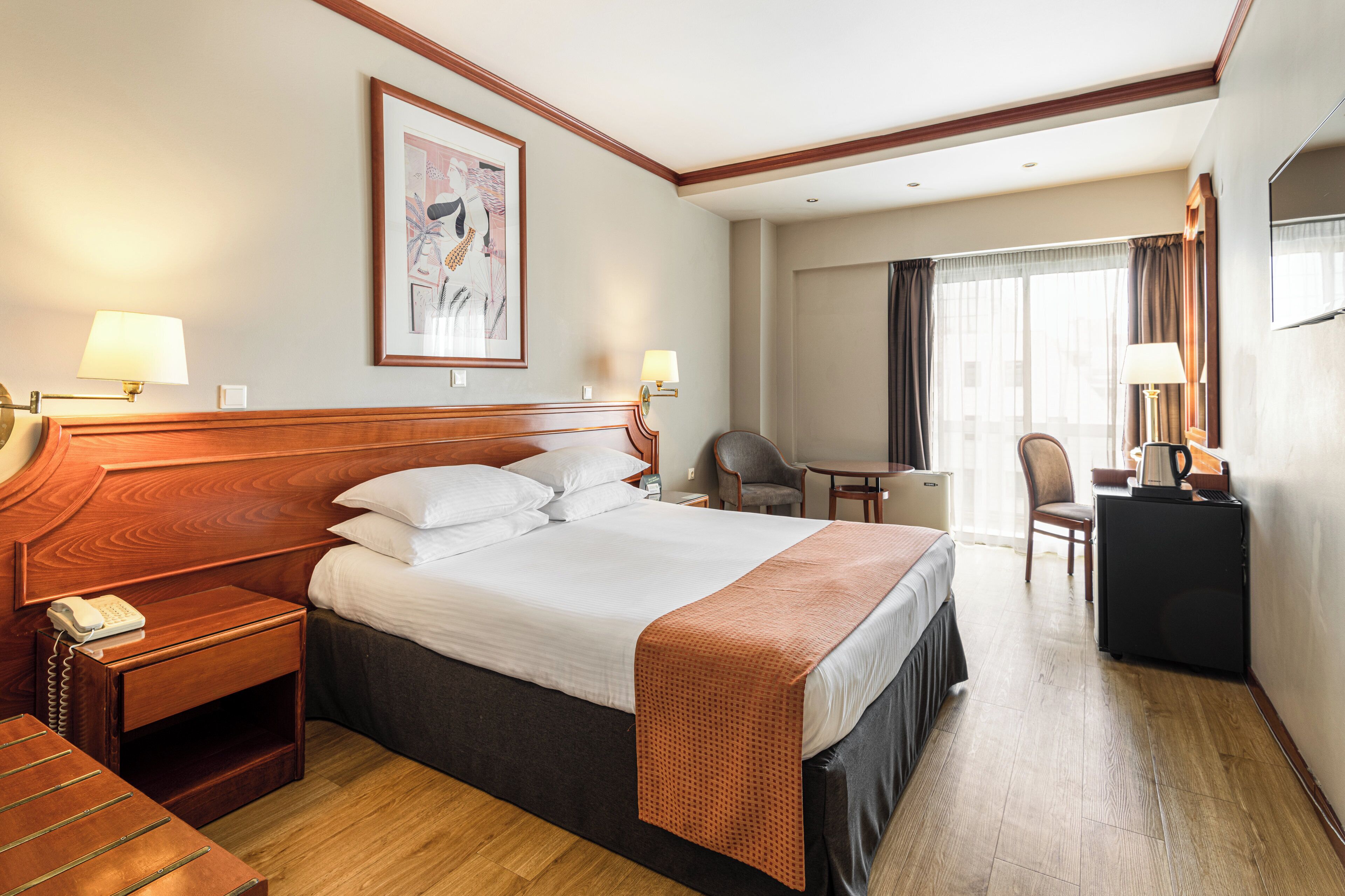 Una habitación de hotel con una cama grande, mesitas de noche, un escritorio y una silla.
