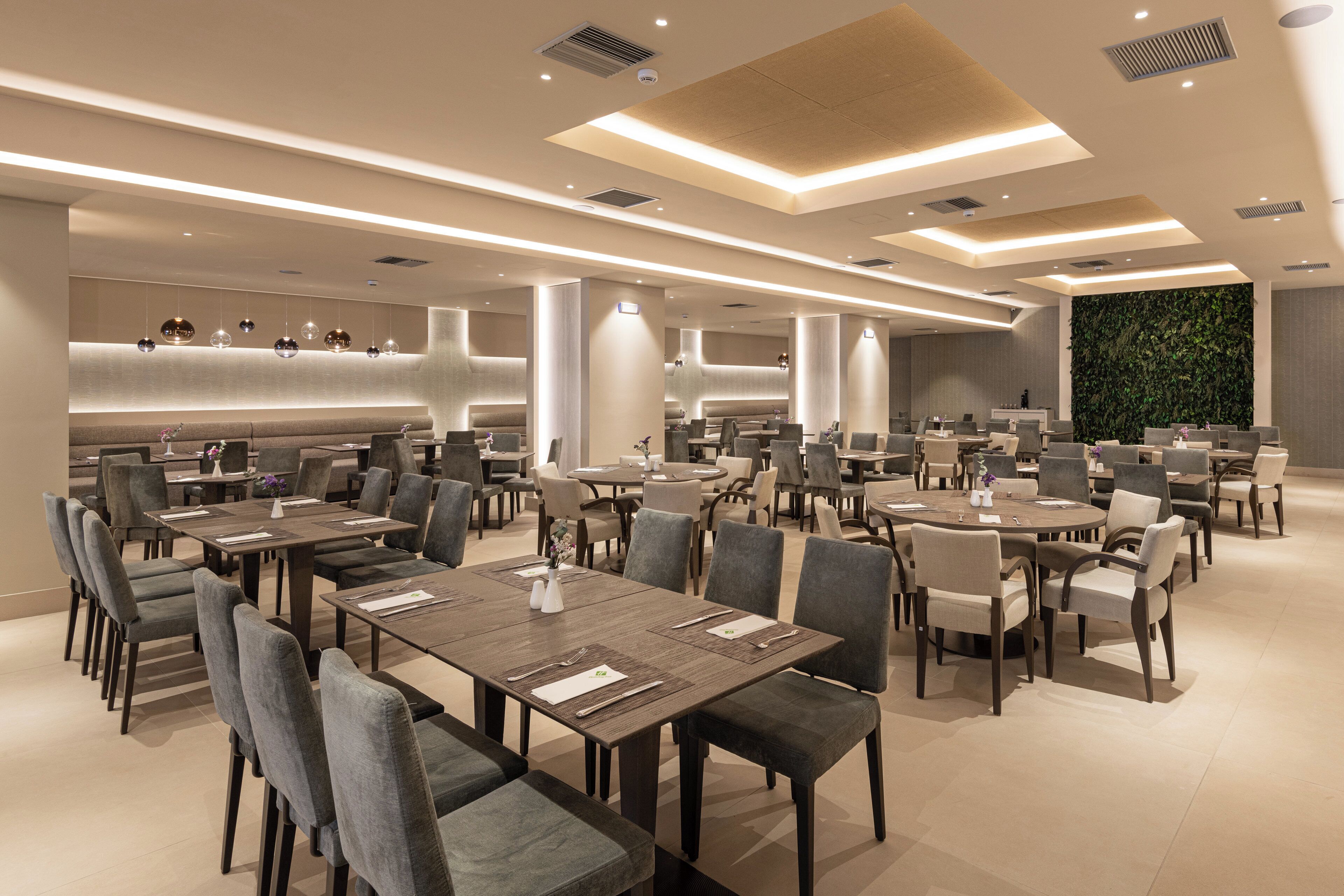 A modern restaurant with multiple dining areas, including round and rectangular tables, and a variety of seating options.