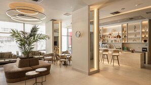 A modern hotel lobby with a seating area, a bar, and a large plant. - Holiday Inn Thessaloniki by IHG (Thessaloniki)