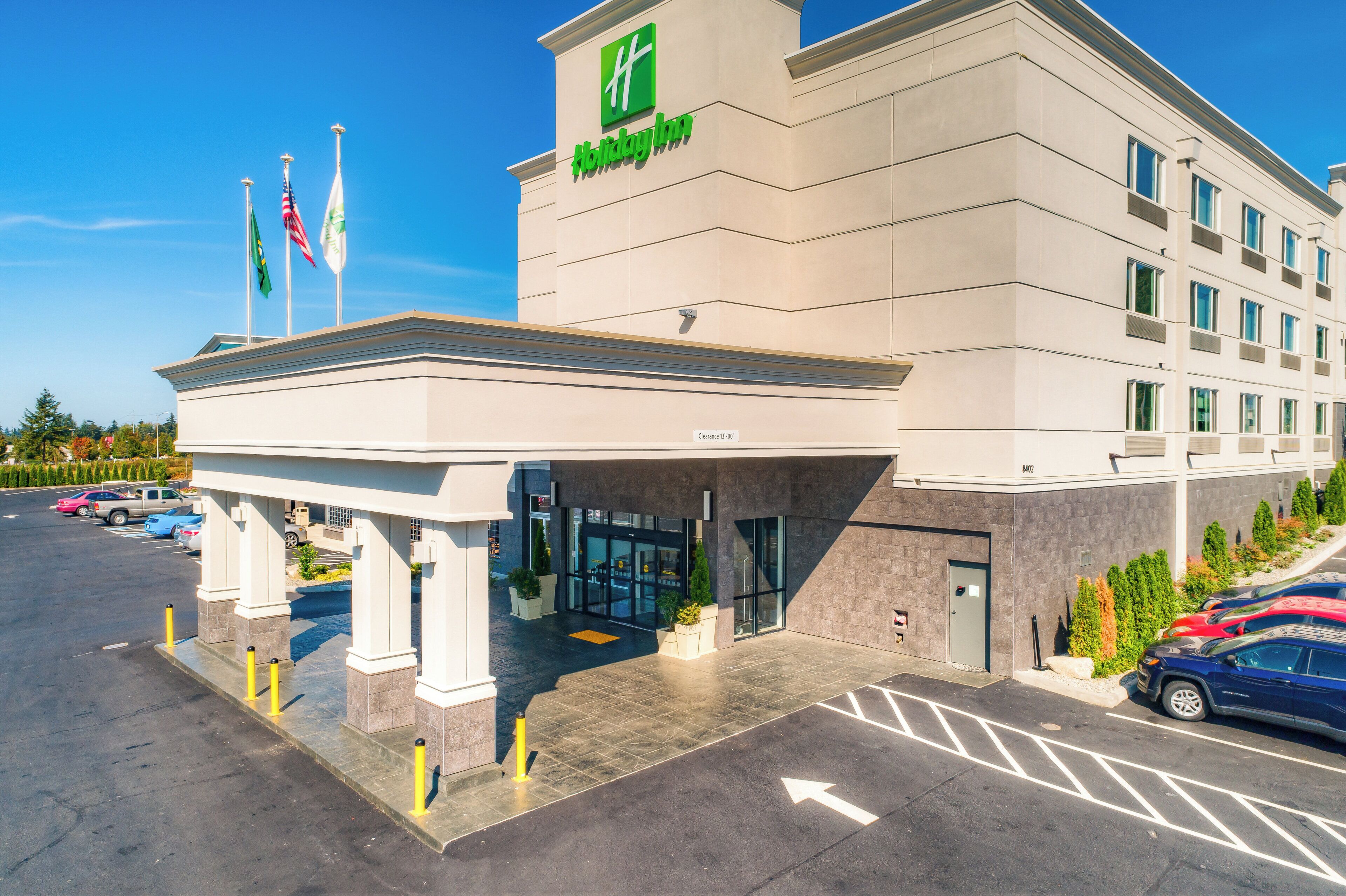 Edificio de Holiday Inn Express, con entrada despejada, estacionamiento y banderas.