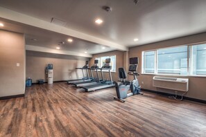 A gym with treadmills, a stationary bike, and a water dispenser. - Holiday Inn Tacoma Mall by IHG (Tacoma)