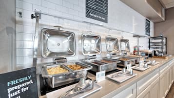 Montaje de bufé con diversas estaciones de comida, incluyendo un cartel que dice "PREPARADO AL MOMENTO, solo para ti".