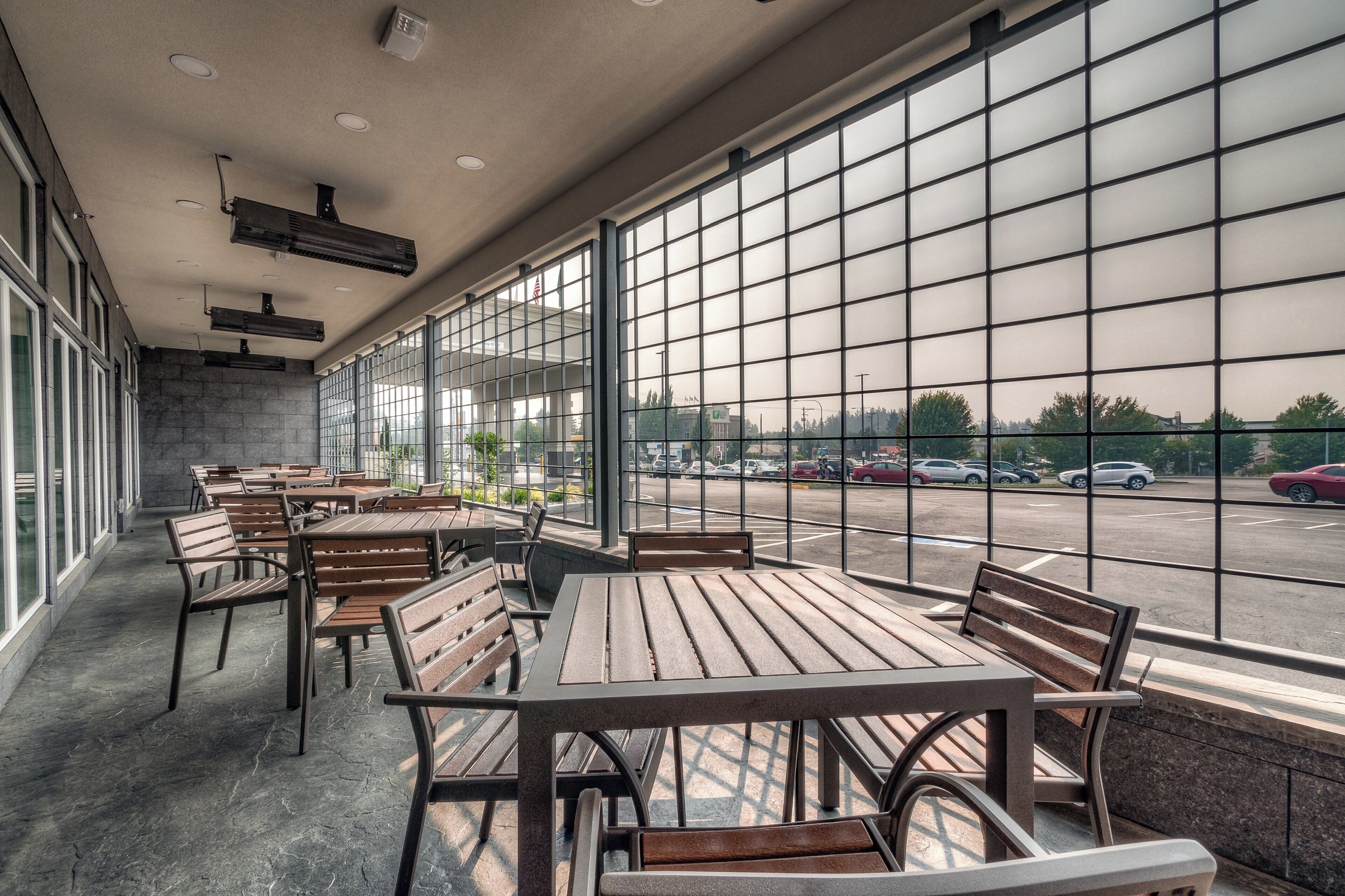 A spacious indoor seating area with tables and benches, large windows with a grid pattern, and a view of a parking lot.