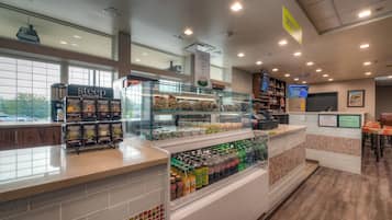 A coffee shop interior with a display of 'steep' tea boxes, a coffee station, and a beverage refrigerator.