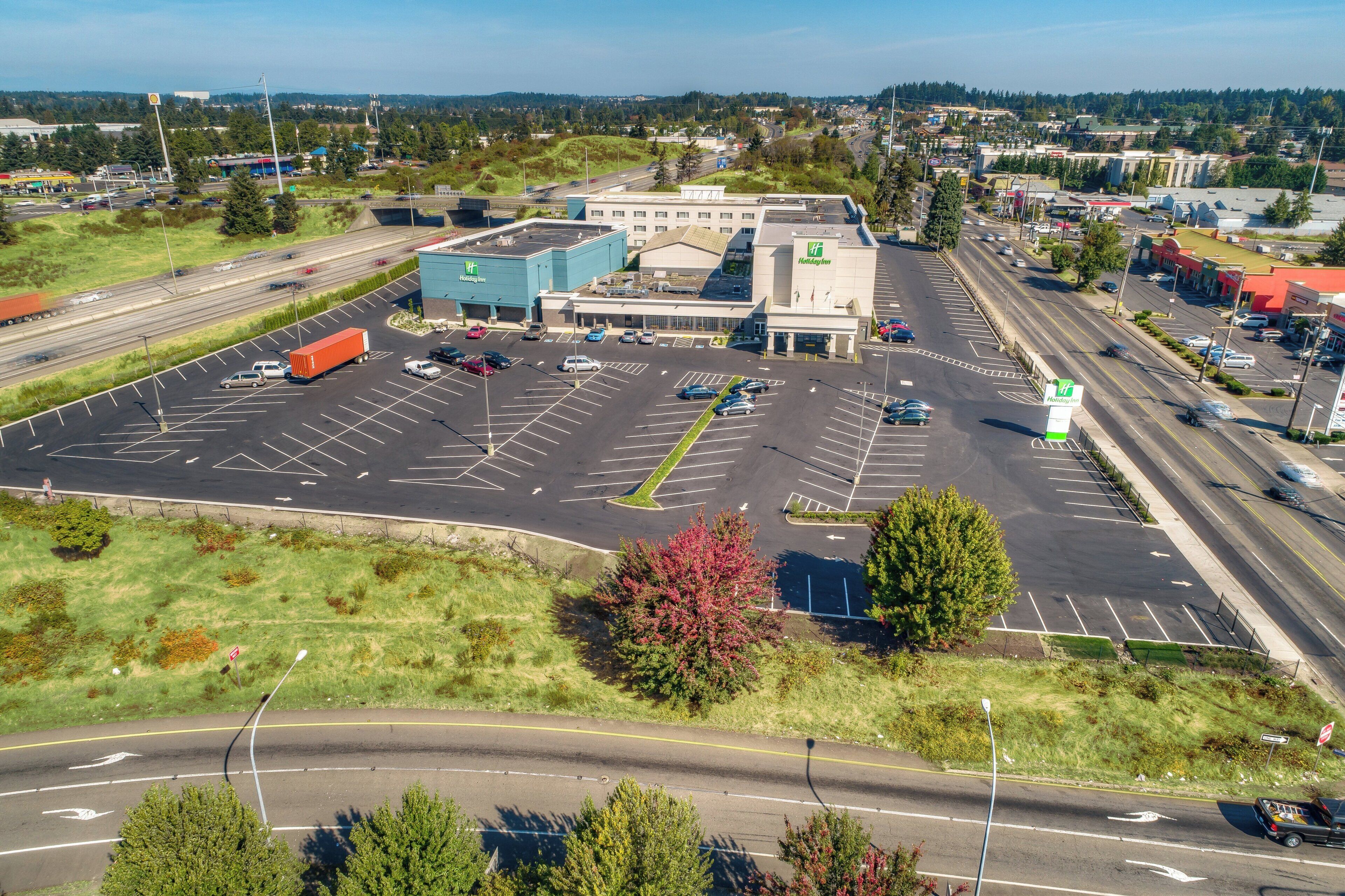 Un hôtel Holiday Inn doté d’un grand parking, de plusieurs voies de circulation et entouré de verdure.