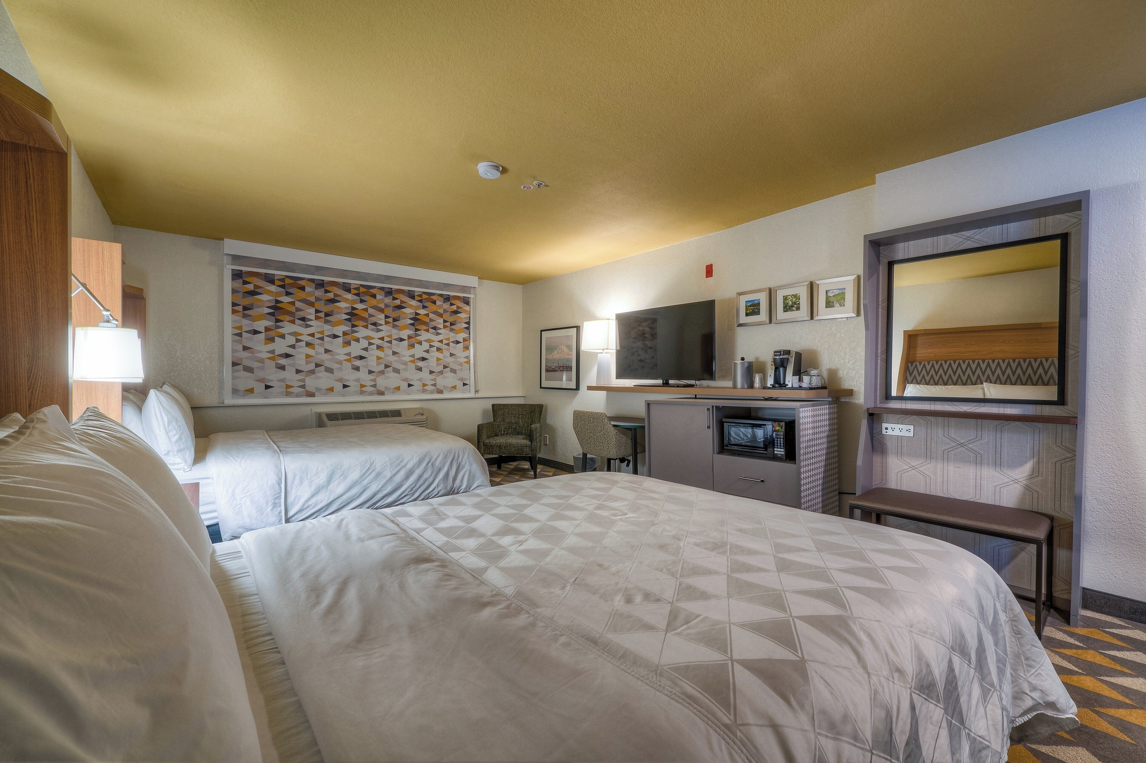A hotel room with two beds, a television, a coffee maker, and a microwave.