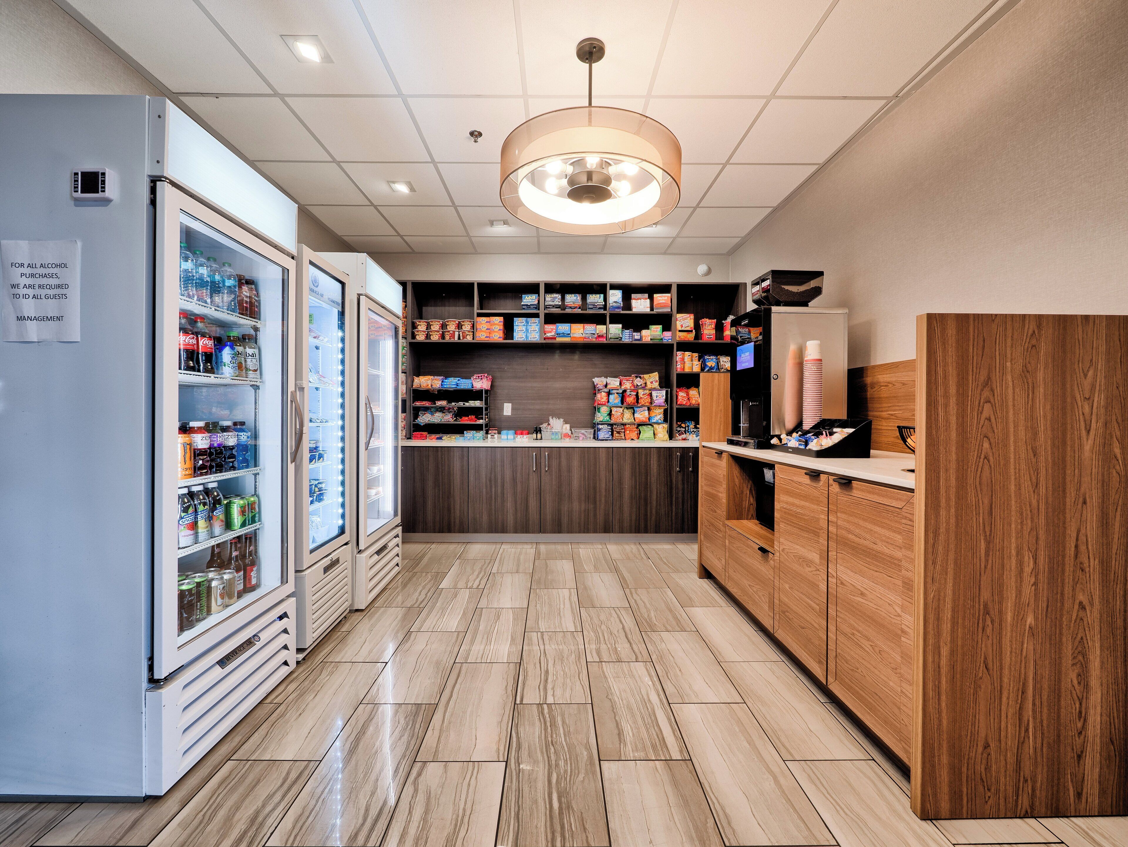 Een schone, goed verlichte snackbar met gekoelde drankautomaten en diverse snacks en dranken.