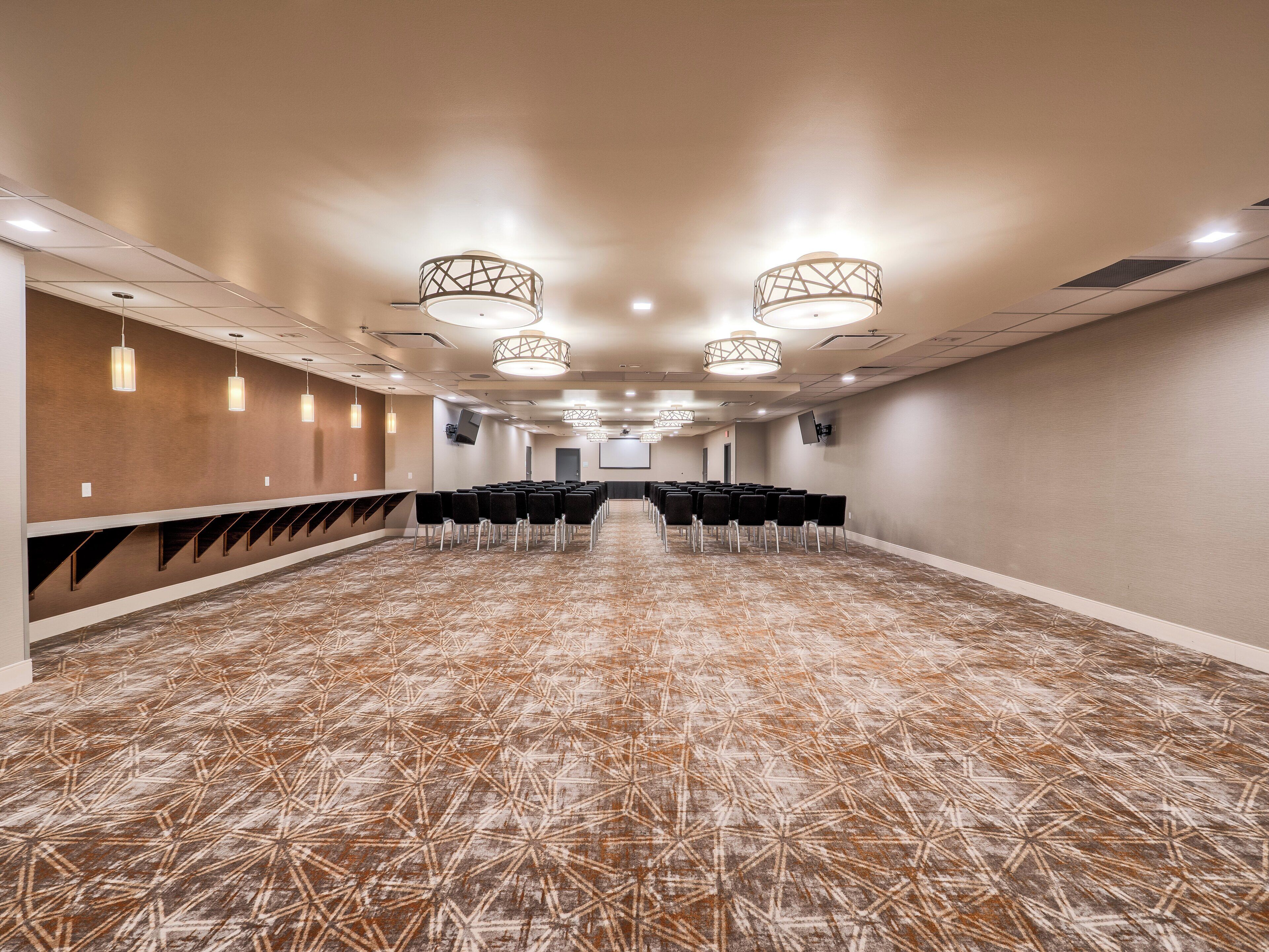 A conference room with rows of chairs, a long table, and a projector screen at the front.